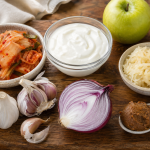 Wooden cutting board with fermented foods including yogurt, kimchi, sauerkraut, and miso alongside fresh garlic, red onion, and a green apple