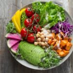 Colorful bowl of fresh vegetables, legumes, and whole grains on a rustic wooden table representing high-fiber foods